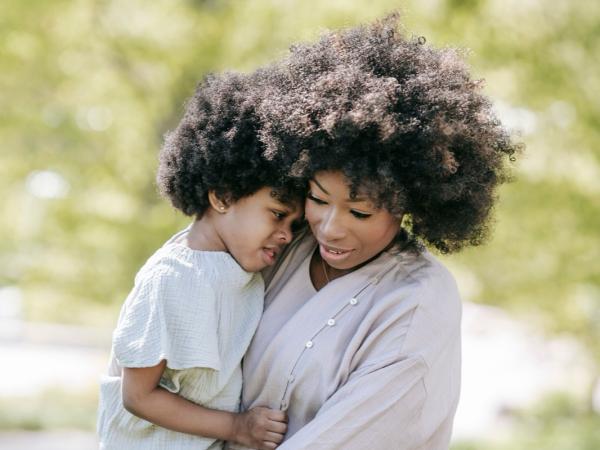 A mother cradles her young son in a tender embrace outdoors