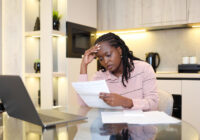 Father and daughter inserting a coin in a piggy bank. Happy African American small girl kid putting money into the piggybank